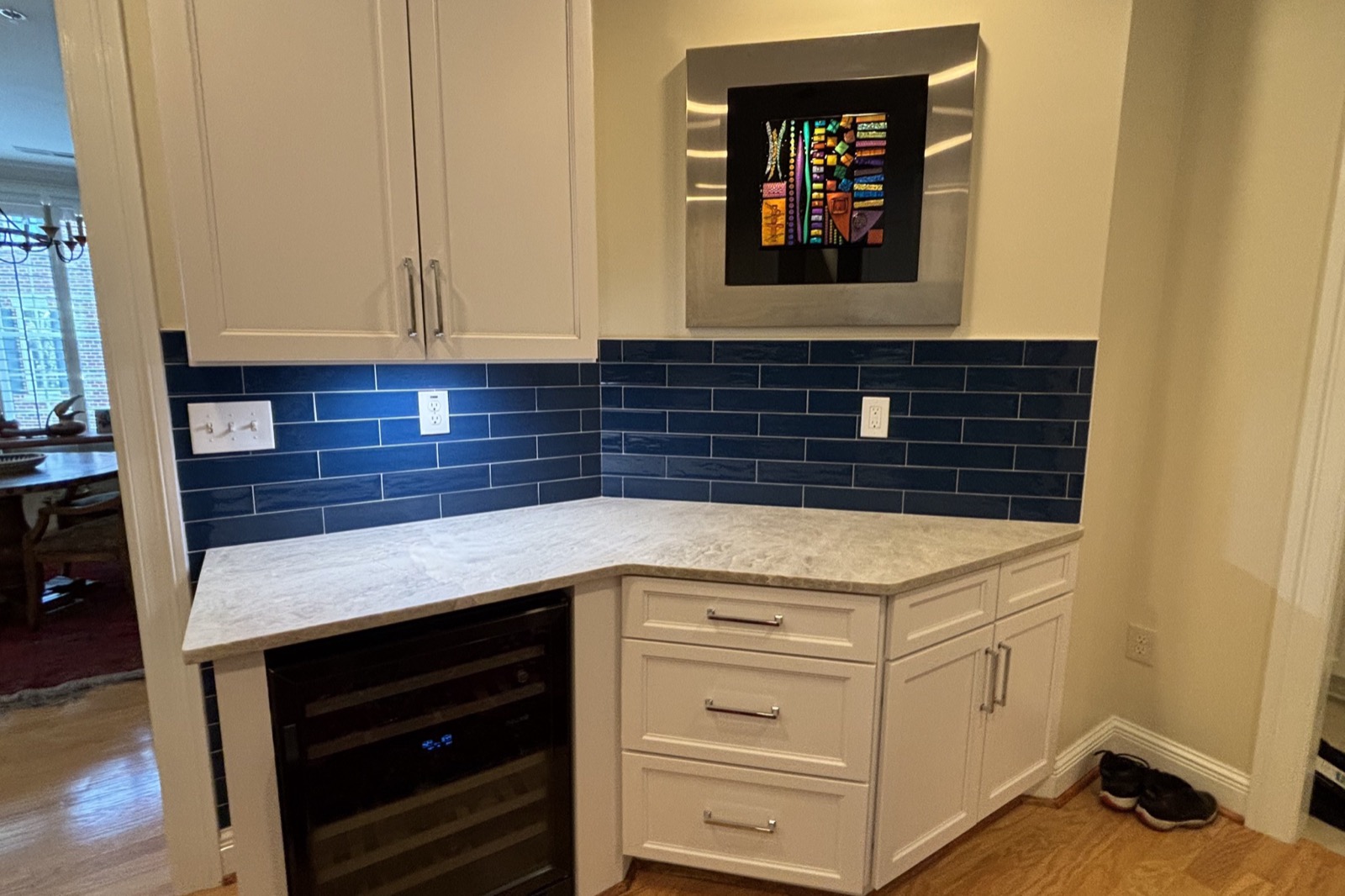 Kitchen built-ins with a navy tile backsplash and wine fridge by Forge Construction Group