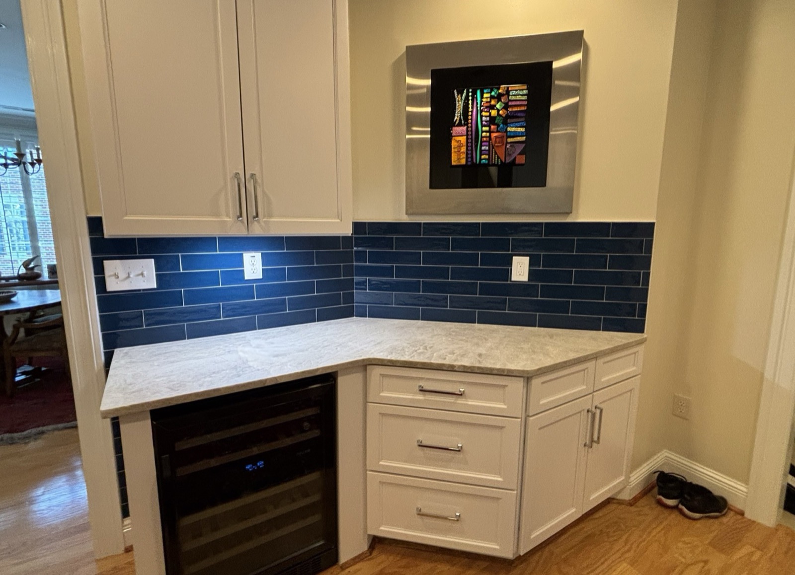Kitchen built-ins with white cabinets, blue tile backsplash and a wine fridge by Forge Construction Group